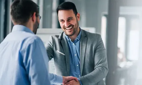 工商管理硕士 graduate smiling 和 shaking h和s after earning leadership position